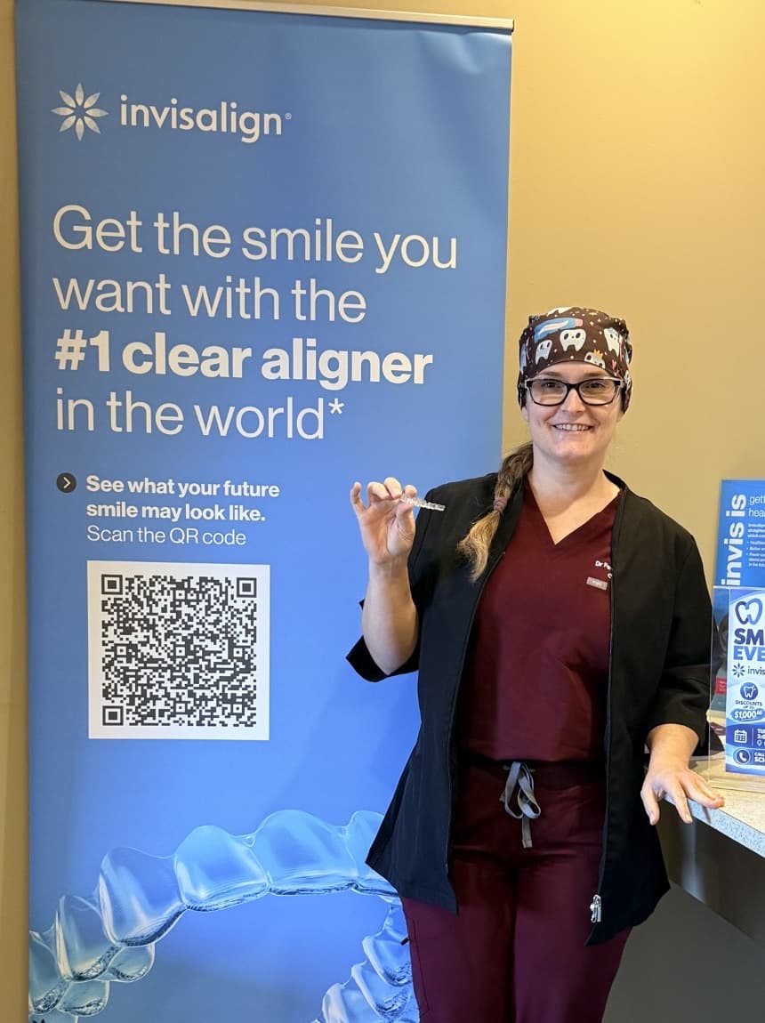 Dr. Fernanda Zanatta holding a clear aligner beside an Invisalign stand at Cobblestone Dental Care
